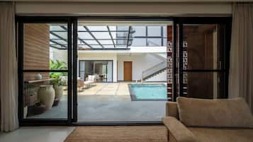 A modern interior with a sliding glass door leading to a pool area, a sofa, and a staircase.