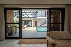 Um interior moderno com uma porta de vidro deslizante que dá para uma área de piscina, um sofá e uma escada.