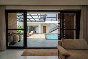 Um interior moderno com uma porta de vidro deslizante que dá para uma área de piscina, um sofá e uma escada.