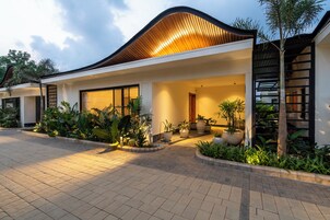 Uma casa moderna com telhado curvo, janelas amplas e um jardim bem cuidado.