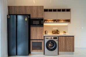 A compact kitchen with a black refrigerator, a microwave, a dishwasher, and wooden cabinetry.
