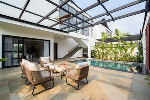 Uma área externa moderna com piscina, móveis de vime e teto de vidro.