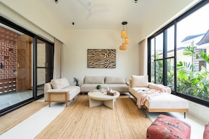 A modern living room with a sofa set, a coffee table, and a view of greenery outside.