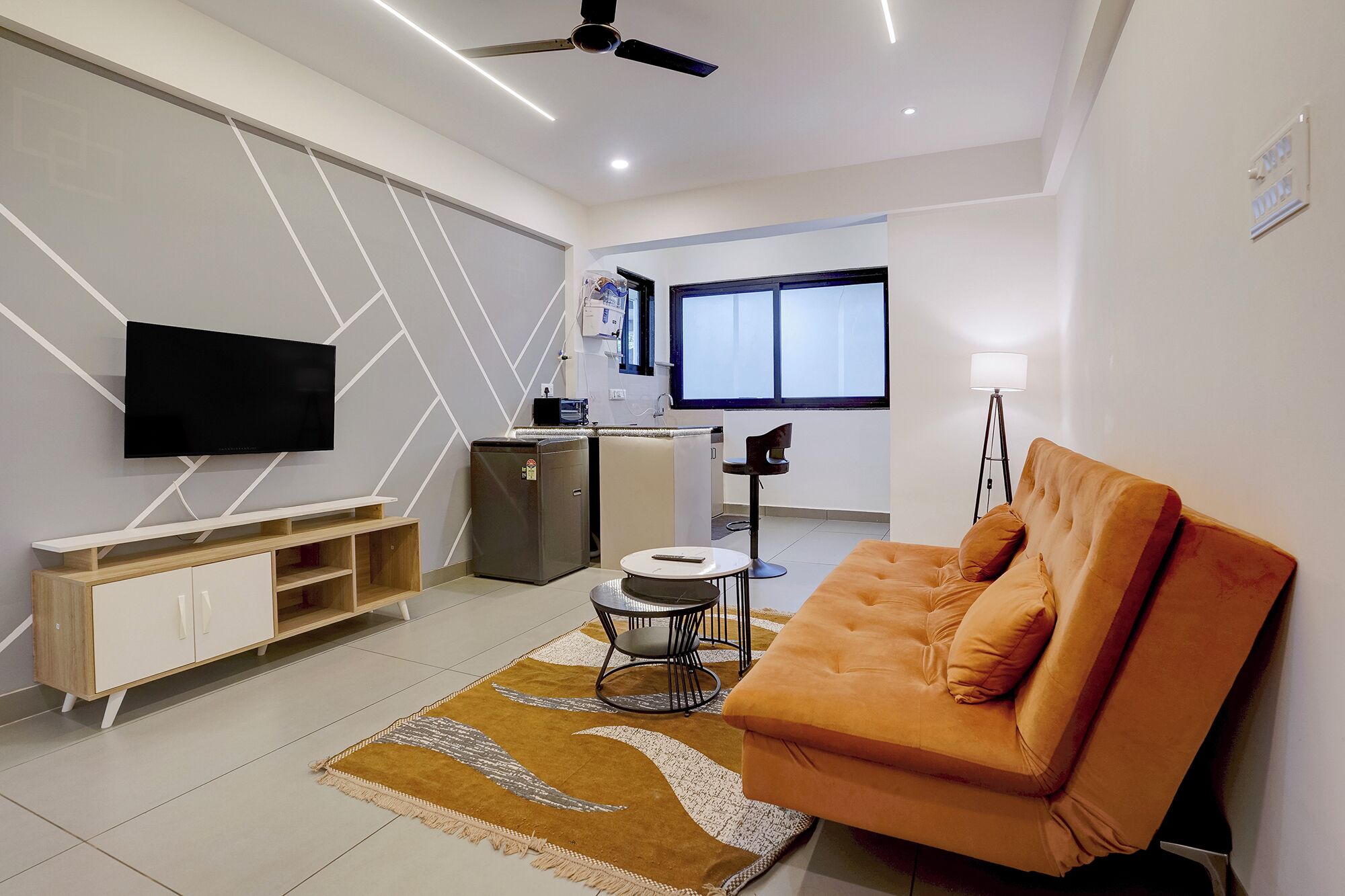 Uma sala de estar moderna com um sofá, uma televisão, uma mesinha e um candeeiro de chão.