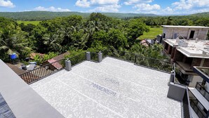Terraço no telhado com vista para uma paisagem verdejante e colinas distantes.