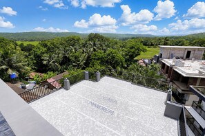 A rooftop terrace with a view of a lush green landscape and distant hills. - FabHotel Casa Mandrem (Mandrem)