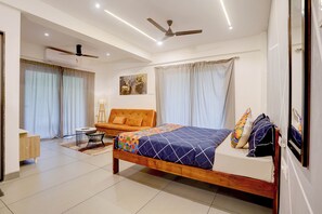 A bedroom with a bed, a sofa, a ceiling fan, and a window with curtains. - FabHotel Casa Mandrem (Mandrem)