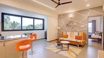 Uma sala de estar moderna com um sofá, cadeiras, uma mesa de jantar e um ventilador de teto.
