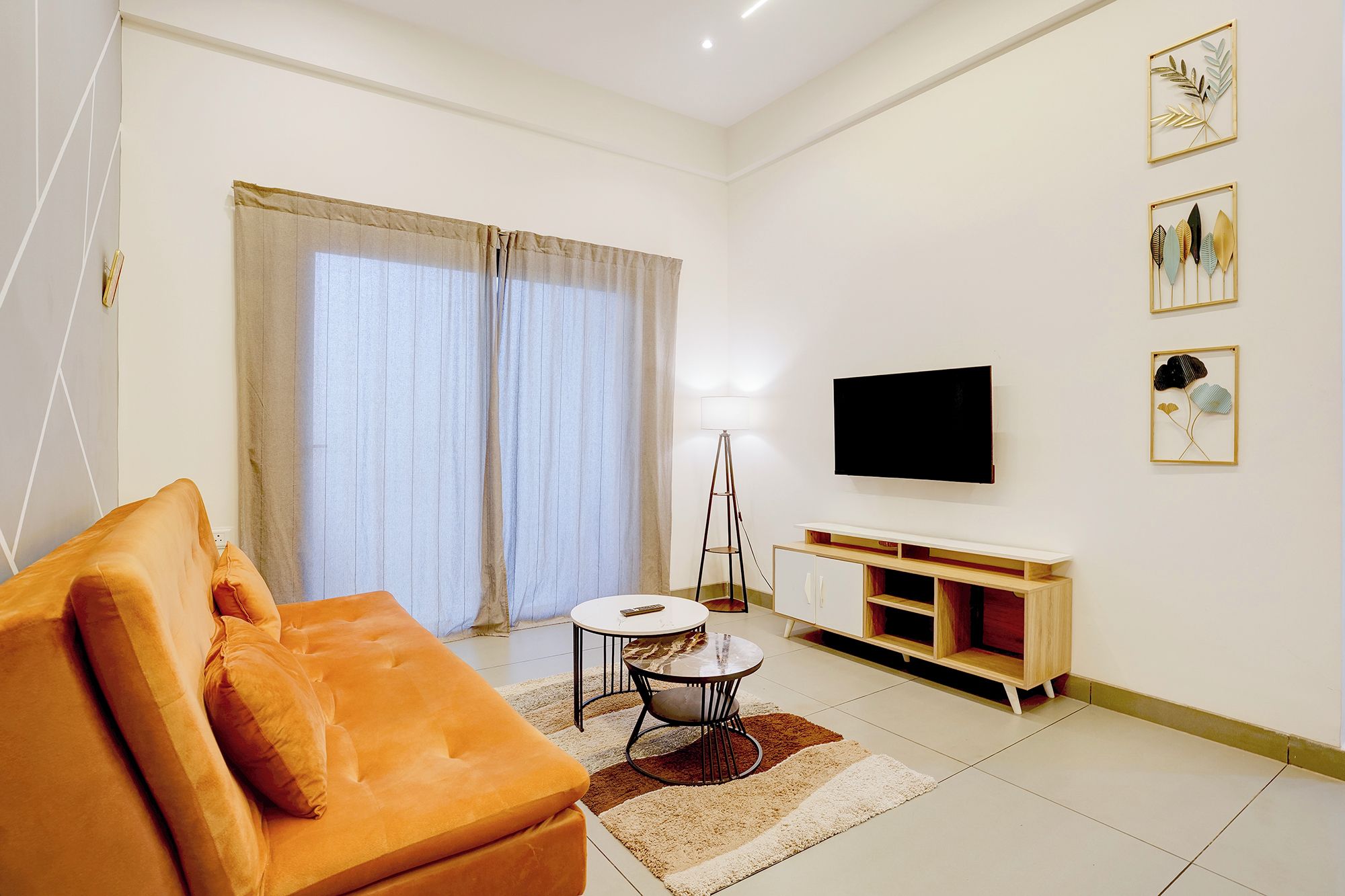 Una sala de estar moderna con un sofá, un televisor, una lámpara y obras de arte en la pared.