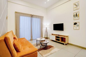 Una sala de estar moderna con un sofá, un televisor, una lámpara y obras de arte en la pared.