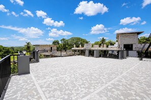 A rooftop terrace with a patterned floor, a metal railing, and a view of the surrounding greenery and clear sky. - FabHotel Casa Mandrem (Mandrem)