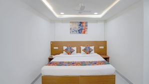 Un dormitorio con cama, ventilador de techo, mesita de noche y un cuadro colgado en la pared.