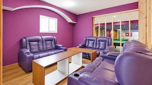 A room with purple walls, a wooden coffee table, and two purple sofas. - Fabhotel Mv Luxury Rooms (Hyderabad)