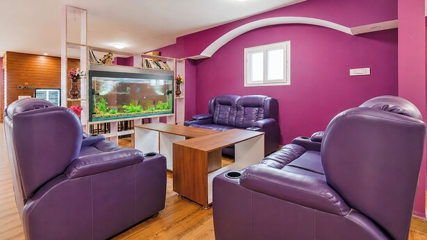 Una sala de estar con sofás de cuero púrpura, una mesa de centro de madera y un acuario grande.