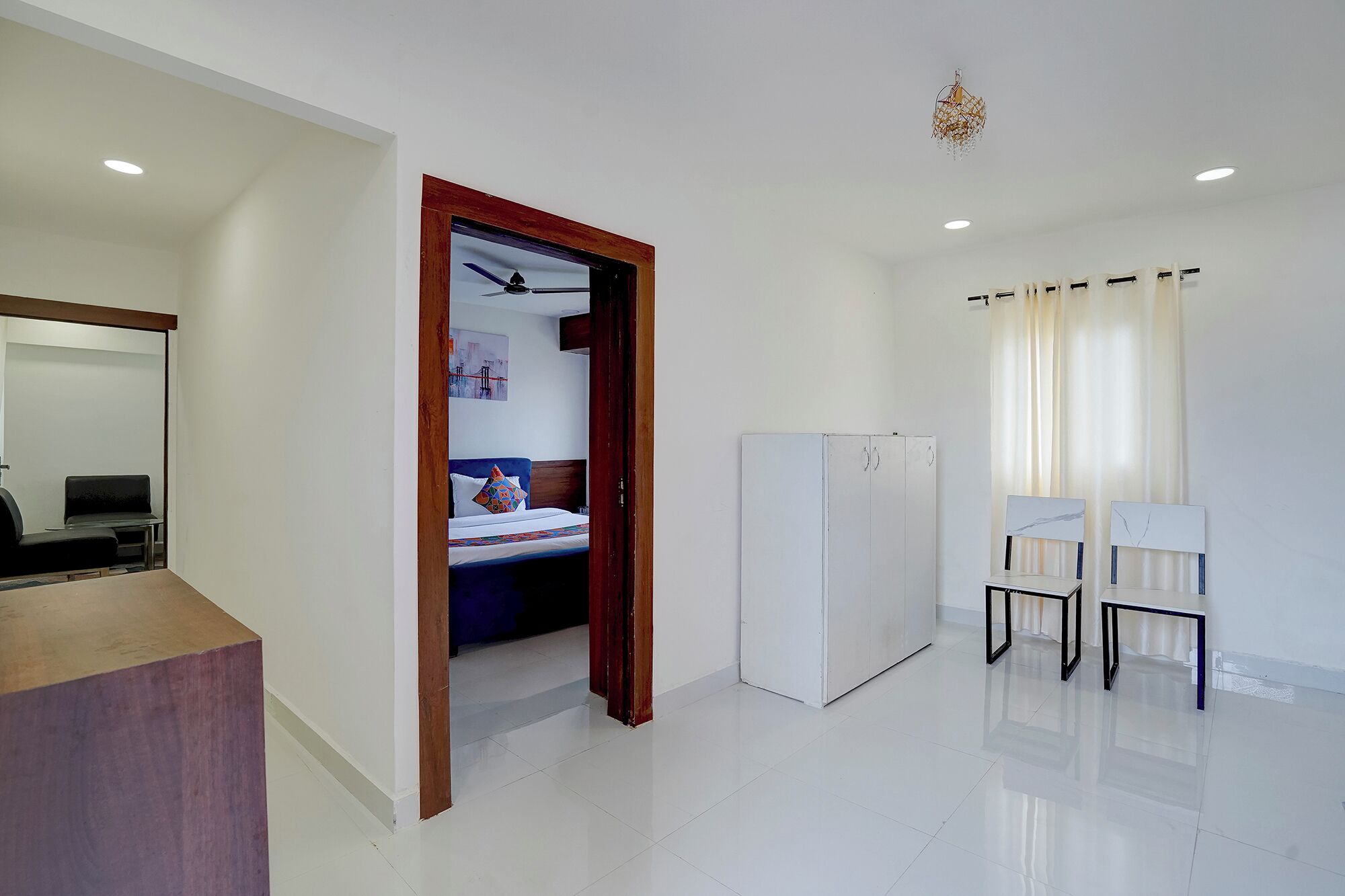 Ein Hotelzimmer mit Bett, Schreibtisch, Stuhl, Kleiderschrank und Deckenventilator.