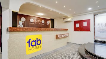 Zona de recepción de un hotel con mostrador, un reloj y un cartel de 'Tab Hotels'.