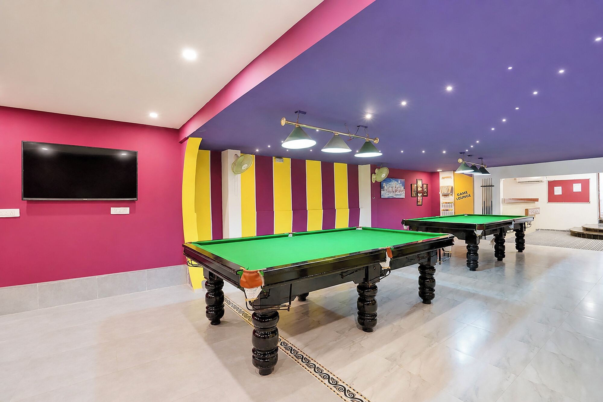 A pool table area with two tables, a flat-screen TV, and a 'Game Lounge' sign.