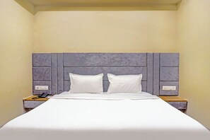 A single bed with a grey headboard, white bedding, and bedside tables with lamps and phones. - Fabhotel Nest Inn (Mumbai)