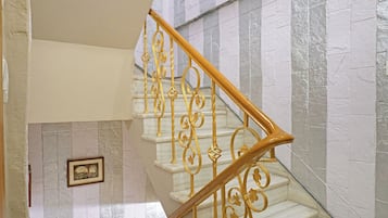 Una escalera con barandillas doradas ornamentadas y escalones de mármol blanco.