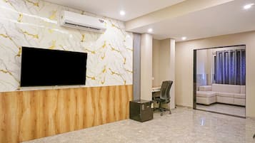 Una zona de recepción moderna con una pared de mármol, un televisor de pantalla plana, un escritorio de madera, una silla de oficina negra y un sofá.