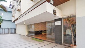 Un edificio moderno con entrada de vidrio, una planta en maceta y un cartel que indica permiso de residencia.