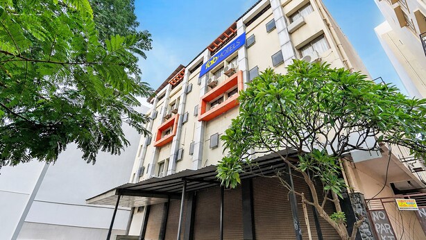 Un hotel de varios pisos con un letrero azul, balcones y una entrada cubierta.