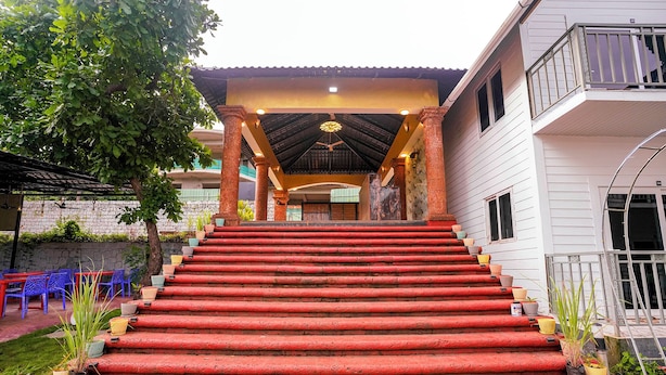 A set of red steps leading to a building with a covered entrance and a balcony. - FabHotel Hill View Cottages (Arpora)