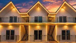 A multi-story building with a symmetrical facade, multiple balconies, and a central staircase. - FabHotel Hill View Cottages (Arpora)