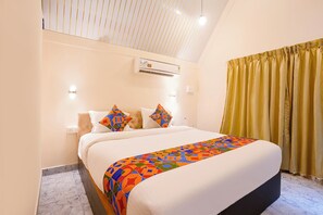 Habitación de hotel con una cama, cabecero, unidad de aire acondicionado, ventana con cortinas y suelo de mármol.