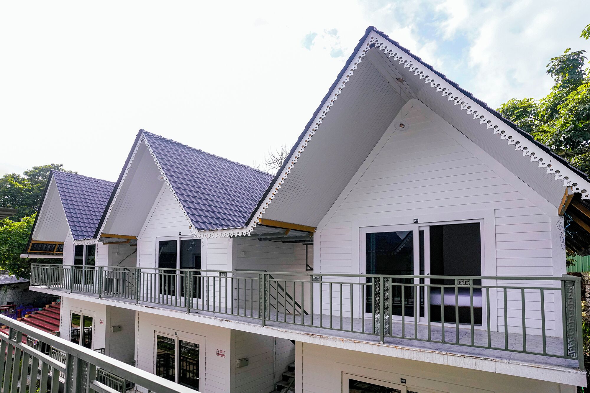 A row of white buildings with blue roofs and balconies.