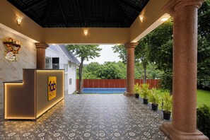 A hotel reception area with a reception desk, a tiled floor, and a view of the surrounding greenery. - FabHotel Hill View Cottages (Arpora)