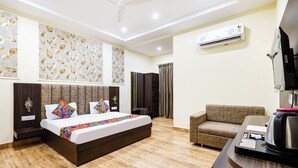 A hotel room with a bed, a sofa, an air conditioning unit, and a television. - Fabhotel Shubh Mangal Grand (Gwalior)