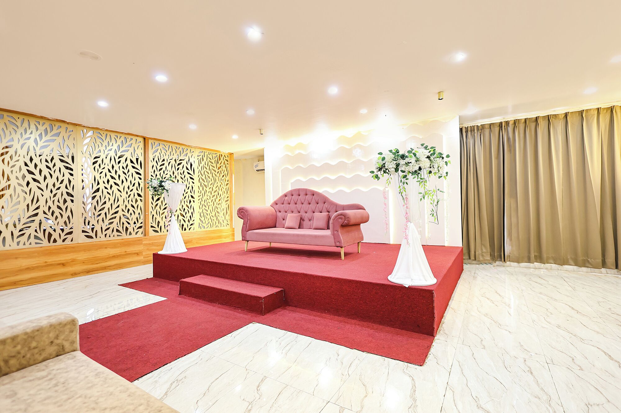 Una habitación con alfombra roja, un sofá rosa y una pared decorativa con diseño estampado.