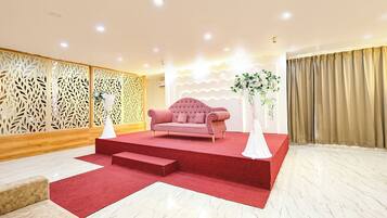 Una habitación con alfombra roja, un sofá rosa y una pared decorativa con diseño estampado.