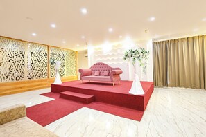 Una habitación con alfombra roja, un sofá rosa y una pared decorativa con diseño estampado.