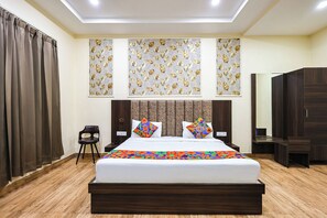 A hotel room with a large bed, a wooden headboard, a chair, and a wardrobe. - FabHotel Shubh Mangal Grand (Gwalior)