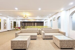 Un amplio vestíbulo de hotel con zonas de estar, un escenario y un candelabro.