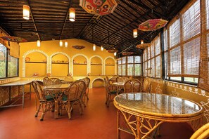 A restaurant interior with high ceilings, wicker furniture, and decorative lighting. - FabHotel Shubh Mangal Grand (Gwalior)