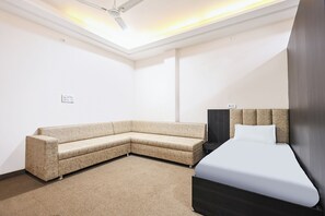 Una habitación de hotel moderna con un sofá curvo, una cama con cabecera oscura y un ventilador de techo.