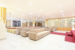 A spacious lobby with rows of beige sofas, a red carpet, and a decorative wall with intricate patterns. - FabHotel Shubh Mangal Grand (Gwalior)