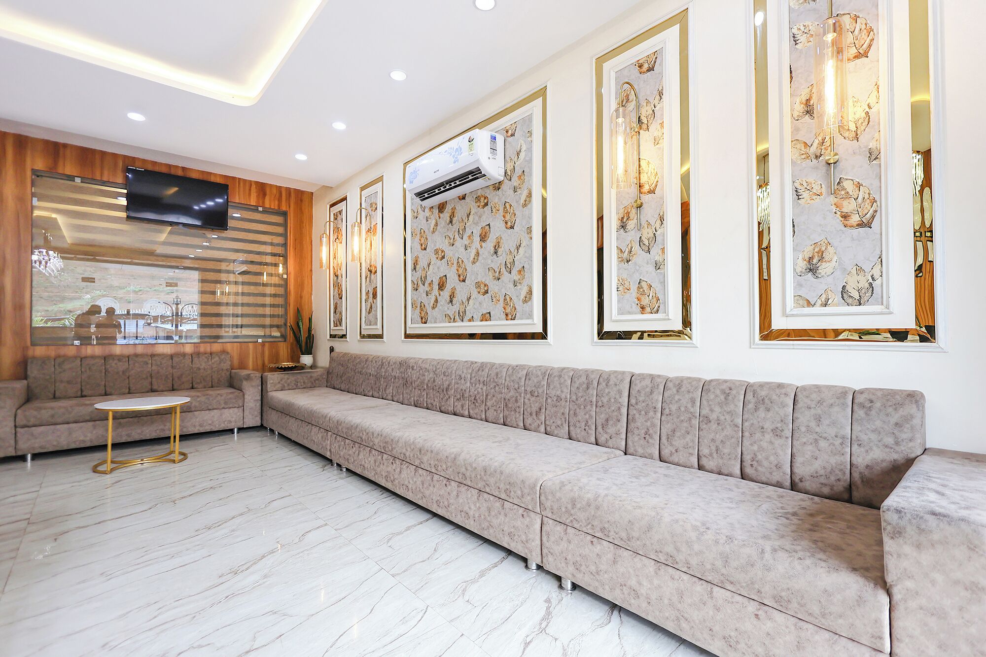Una sala moderna con un sofá color beige, una mesita redonda y cuadros en la pared.