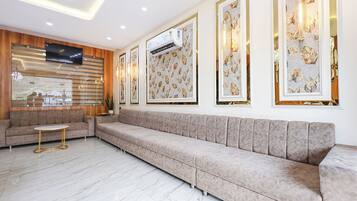 Una sala moderna con un sofá color beige, una mesita redonda y cuadros en la pared.