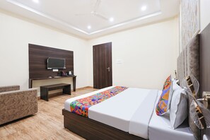Una habitación de hotel con una cama, un escritorio, un televisor y un armario.