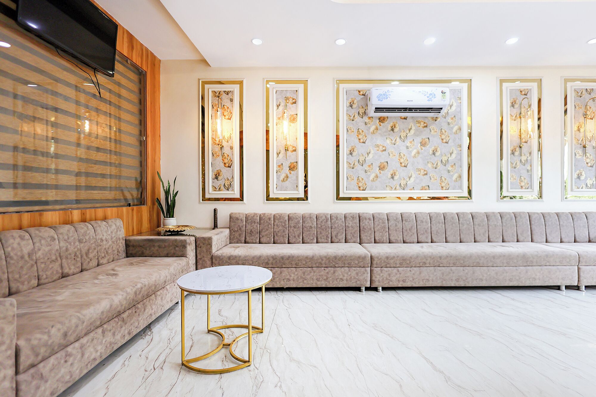 Una sala moderna con un sofá modular, una mesa de centro redonda y obras de arte enmarcadas en la pared.