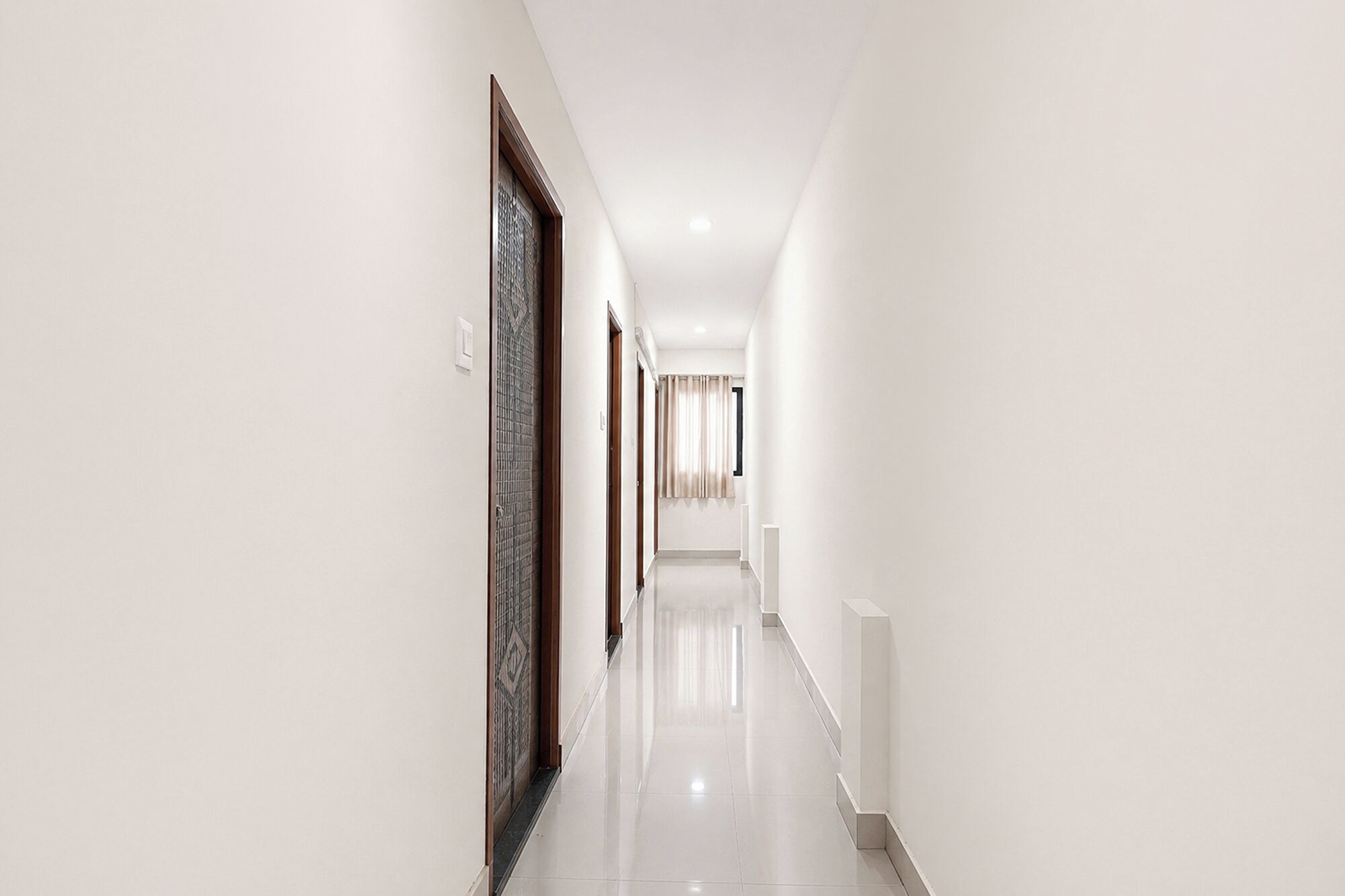 A long, narrow hallway with white walls and a glossy floor.