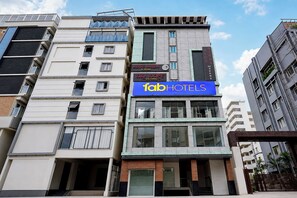 A multi-story building with a prominent blue sign for 'fabHOTELS' indicating a hotel. - FabHotel Blue Birds (Bengaluru)