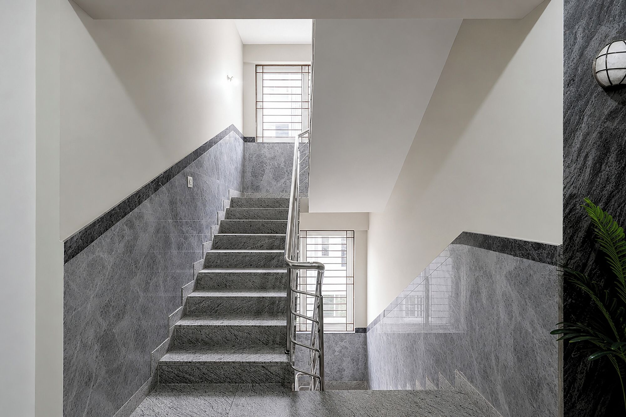 Una escalera con barandilla que conduce a un rellano con ventanal.