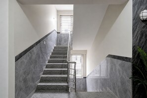 A staircase with a handrail, leading to a landing with a window. - Fabhotel Blue Birds (Bengaluru)