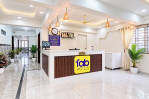 A hotel reception area with a reception desk, a clock, and a reception sign. - FabHotel Blue Birds (Bengaluru)