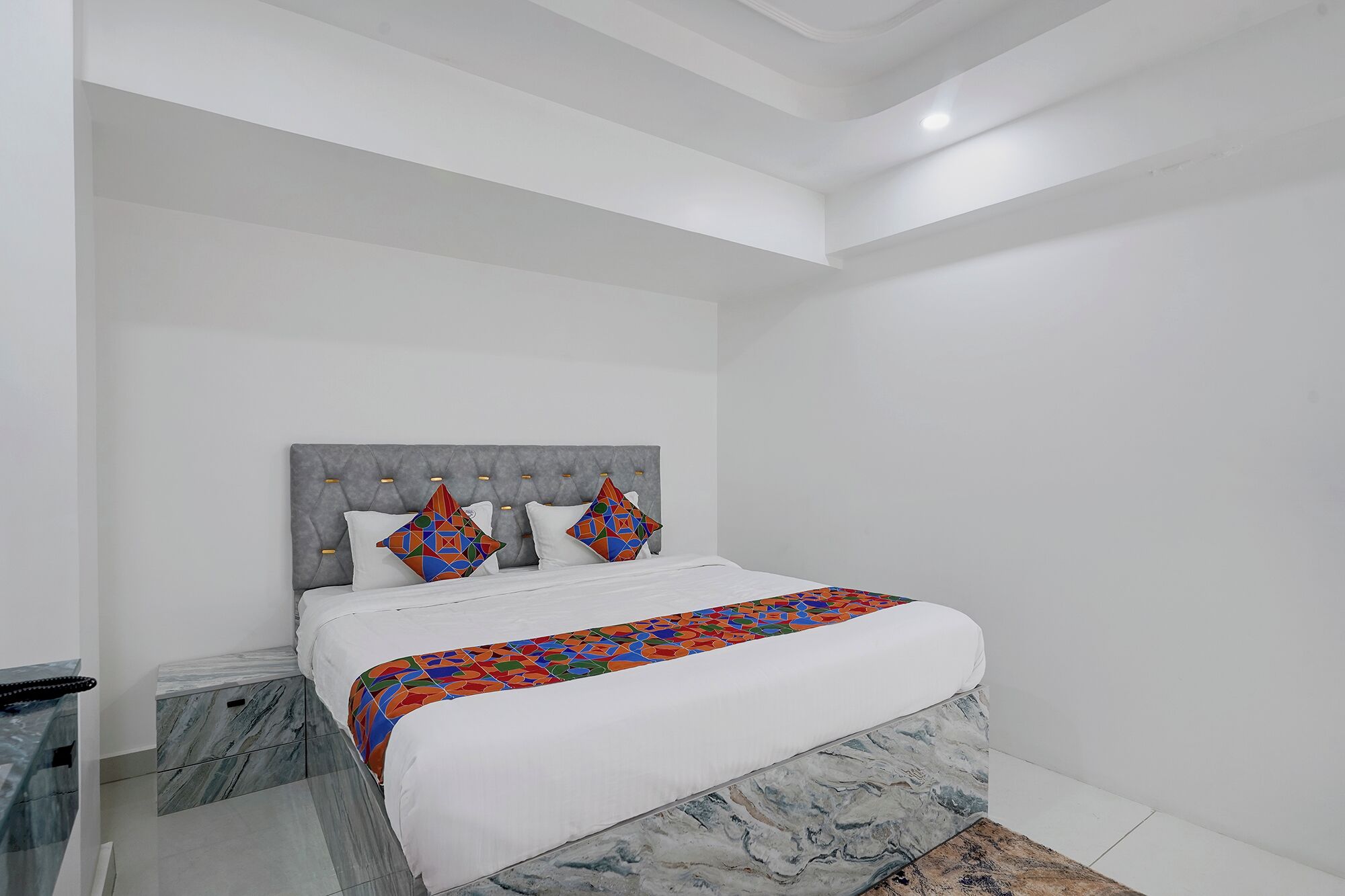 Une chambre à coucher moderne avec un lit, une table de chevet et un banc à motifs de marbre.
